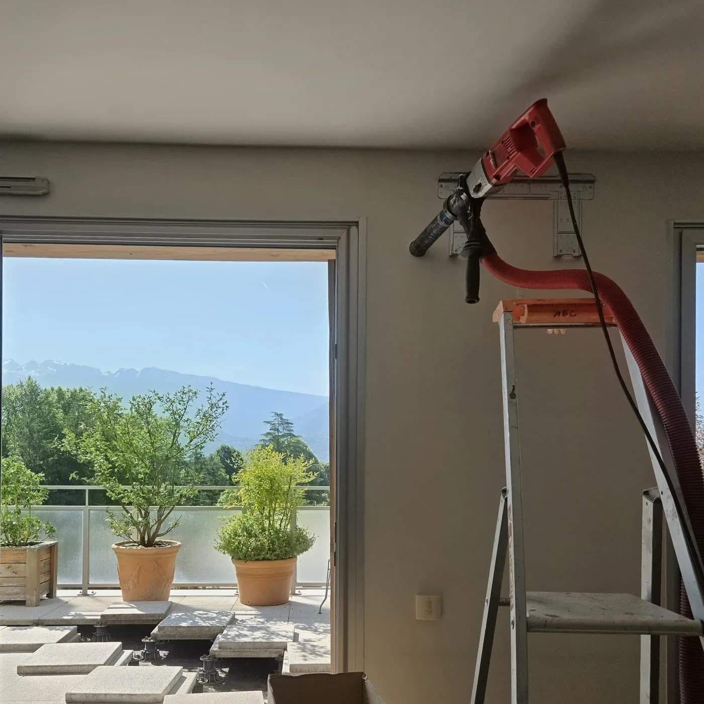 Carotteuse à sec avec aspiration intégrée en action sur la terrasse d'un appartement à Corenc avec vue Belledonne, par Air Eco Clim