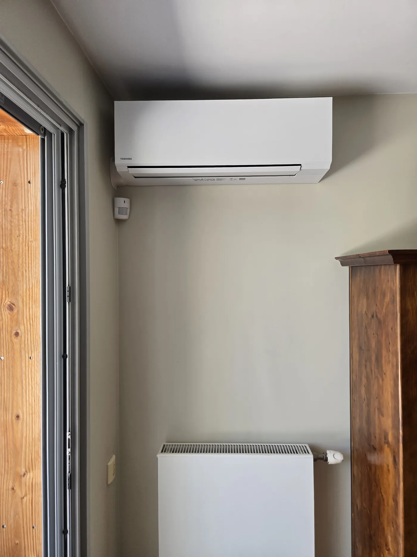 Unité intérieure de climatisation murale Toshiba Shorai Edge installée sur un mur en bois à Corenc, sans goulotte apparente