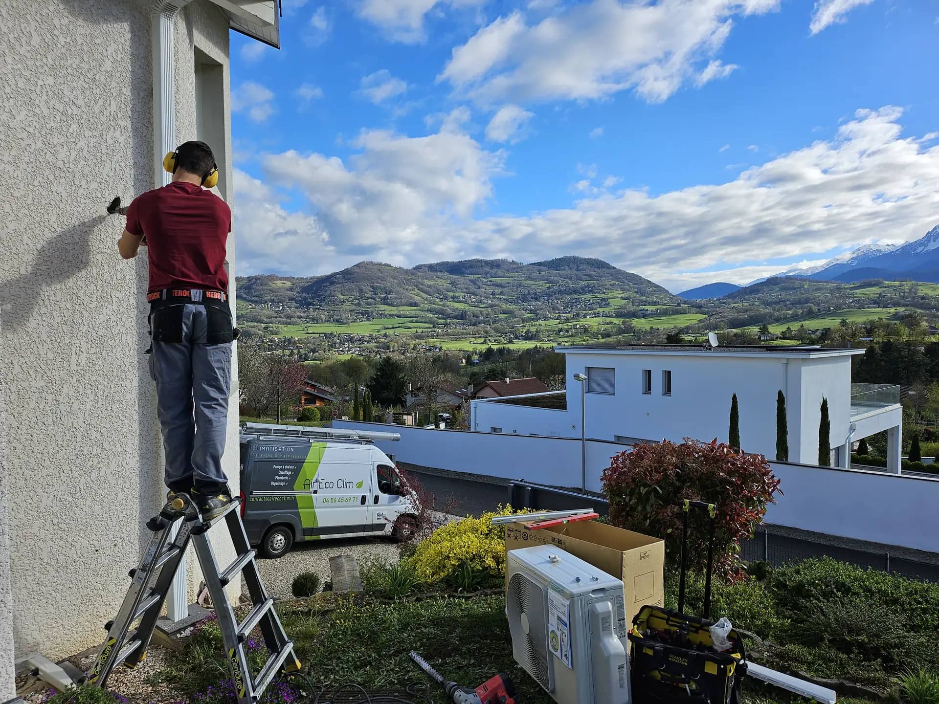 Technicien Air Eco Clim installant une pompe à chaleur à Brié-et-Angonnes, vue sur le massif de Belledonne